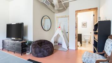 Cozy living space with a flat-screen TV, bean bag chair, and potted plant.