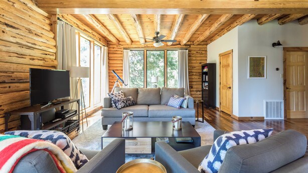 L’intérieur d’une cabane en rondins comprend un salon avec un canapé, une table basse et un téléviseur.