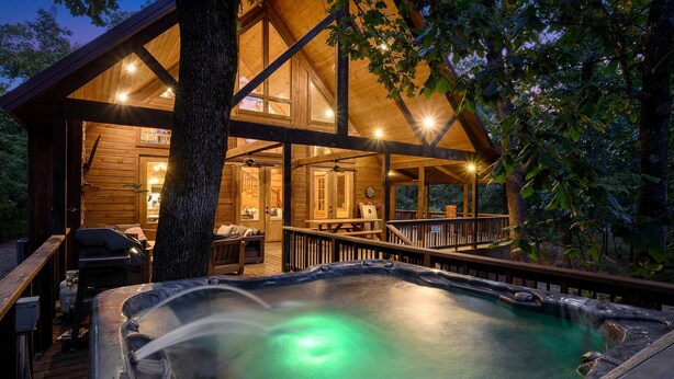 Una cabaña de madera con jacuzzi, terraza y zona de estar al aire libre.