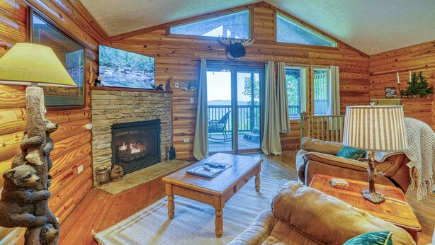 A log cabin interior with a fireplace, wooden furniture, and a view through the glass door. - FREE Dollywood and Attractions daily with stay MTN View Cabin Pool Table Hot tub (Gatlinburg)