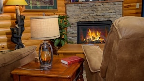 A cozy living room with a fireplace, a lamp, a couch, and a bookshelf. - FREE Dollywood and Attractions daily with stay MTN View Cabin Pool Table Hot tub (Gatlinburg)