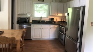 A kitchen with white cabinets, a stainless steel refrigerator, a microwave, and a coffee maker. - Great Fishing! Quiet & Relaxing!  Close to Casino & Mingo Falls! (Cherokee)