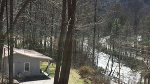 A small cabin with a single window and a porch, surrounded by trees and a snow-covered landscape. - Great Fishing! Quiet & Relaxing!  Close to Casino & Mingo Falls! (Cherokee)