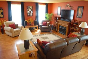 A living room with a sofa, armchairs, a television, a fireplace, and a bookshelf.