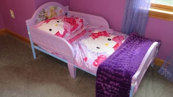 Een kinderbed met een beddegoed met Hello Kitty en een paarse deken.