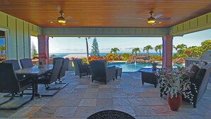 A covered outdoor area with a pool, seating, and a view of the ocean.