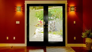 A hotel entrance with a red wall, a glass door, and two wall-mounted lights.