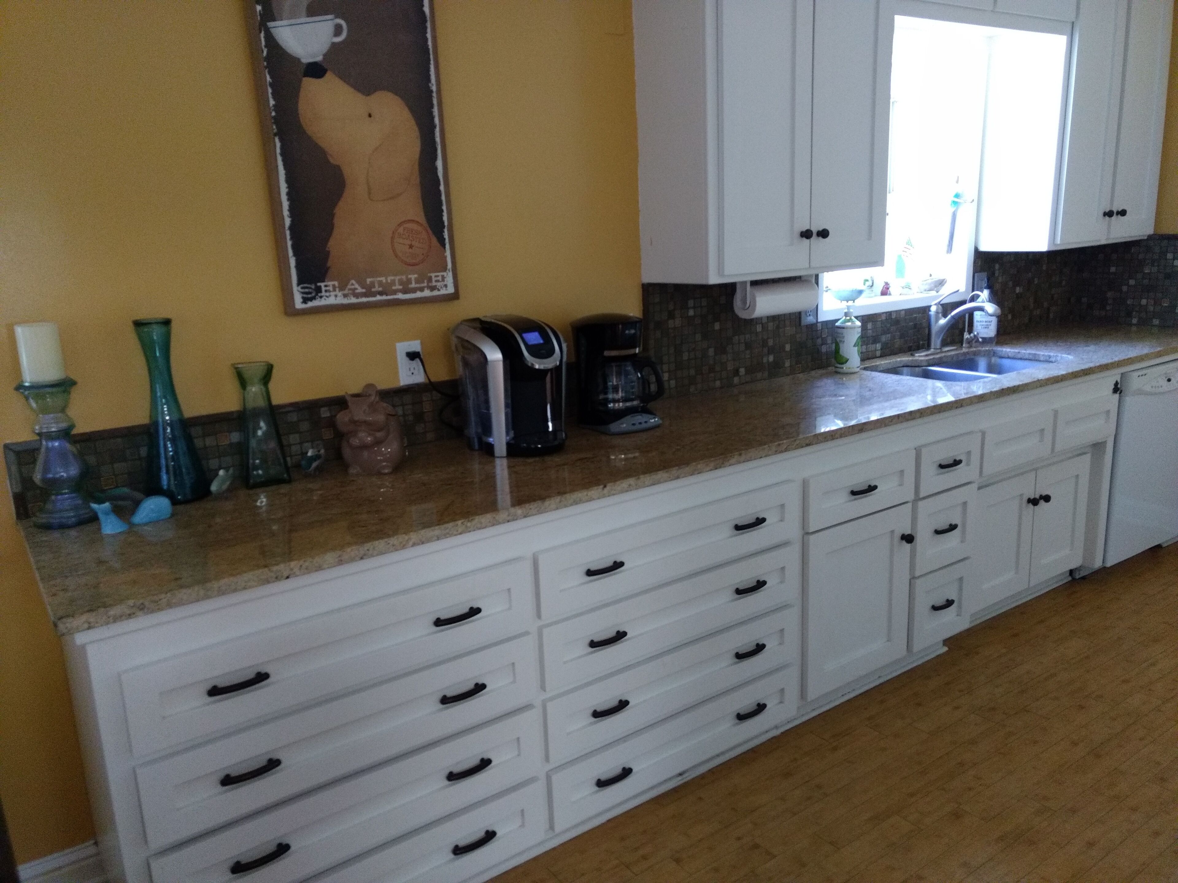 A kitchen with white cabinets, a coffee maker, and decorative vases on the counter.