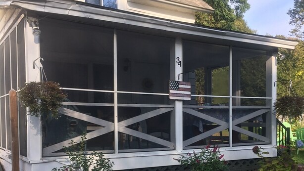 Ein Haus mit überdachter Veranda, einem Steinsschornstein und einem Briefkasten mit der Nummer 34.