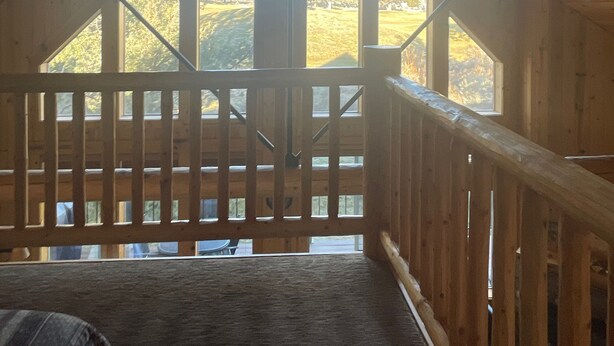 A wooden interior with a high ceiling and a view of a green landscape through large windows. - Remodeled cozy cabin on golf course with hot tub!  (Redmond)