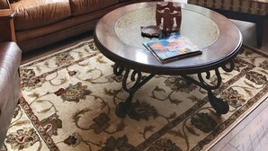 A cozy living room with a leather sofa, a patterned armchair, and a coffee table with a magazine. - Remodeled cozy cabin on golf course with hot tub!  (Redmond)