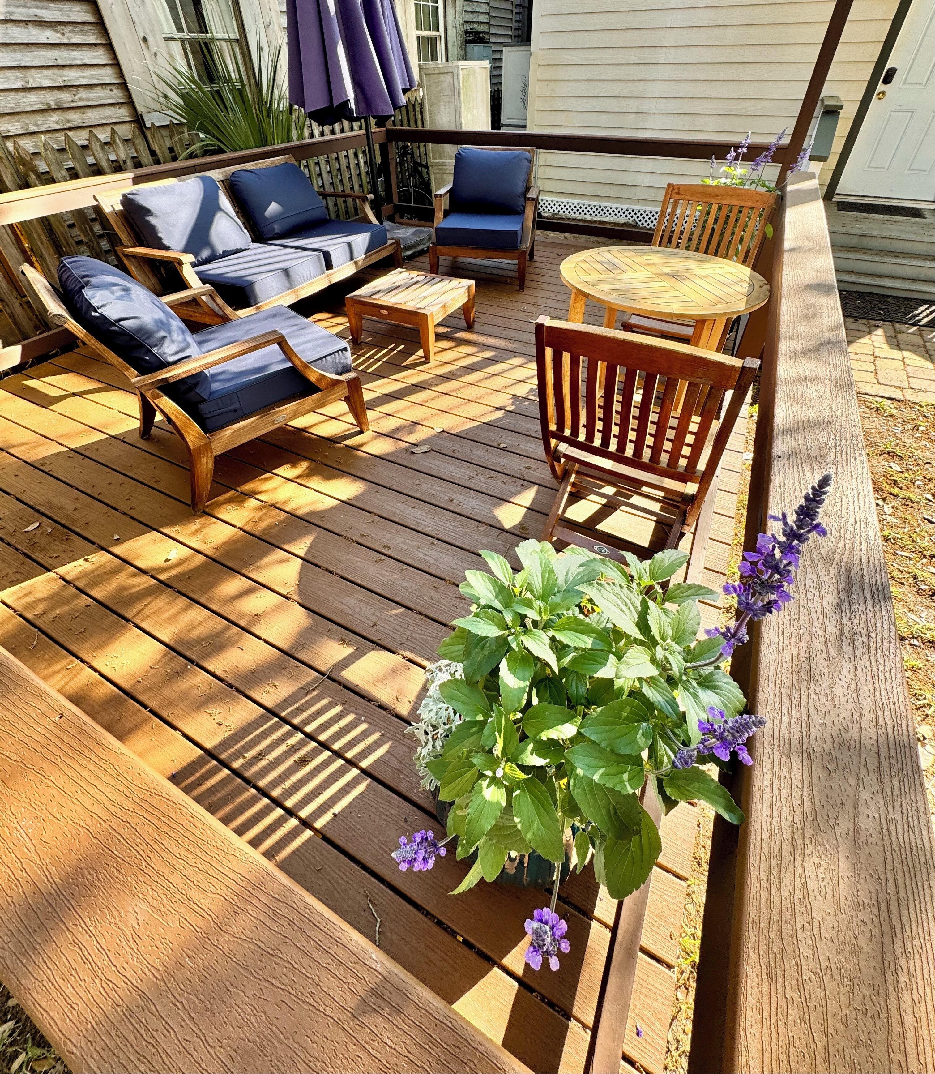 Un terrazzo in legno con mobili da esterno, tra cui sedie e un tavolo.