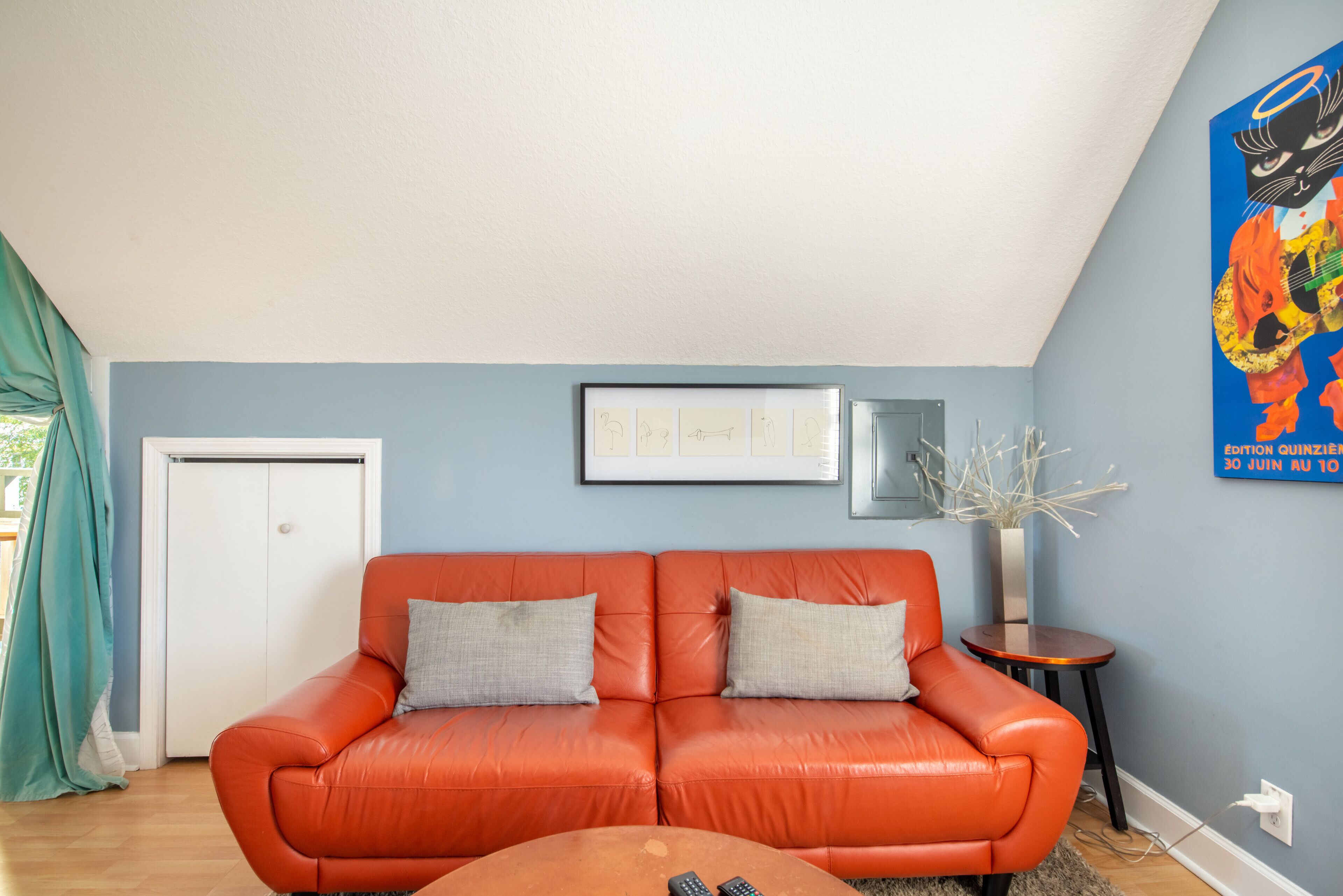 A living room with a red leather sofa, a small round table, and a framed picture on the wall.