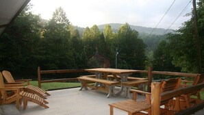 Eine Terrasse im Freien mit Holzmöbeln und Blick auf ein bewaldetes Gebiet.