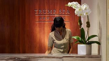 Un comptoir d’accueil, avec un mur en panneaux de bois derrière, sur lequel on peut lire l’inscription « TRUMP SPA NEW YORK ».