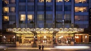 El exterior del Hotel y Torre Trump International, con una entrada imponente, varios pisos y una fachada bien iluminada.
