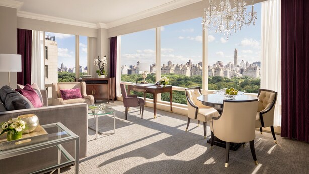 Amplia sala de estar con vista a la ciudad, un candelabro y un comedor con mesa y sillas.