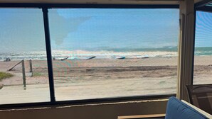 Ein Zimmer mit großem Fenster und Blick auf einen Strand.