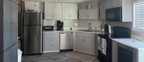 A compact kitchen with a refrigerator, dishwasher, microwave, and stove.