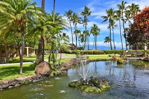 A tropical garden with a pond, palm trees, and a bench. - NEWLY REMODELED 1BR Ground Floor Corner Condo - Dual A/C in Ocean Front Resort. (Lahaina)