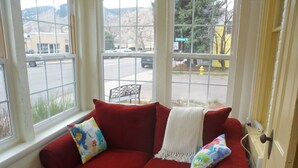 A red sofa with colorful pillows and a white throw blanket in a room with large windows. -  LOVELY 1 Bedroom Apartment in the Heart of Golden (Golden)