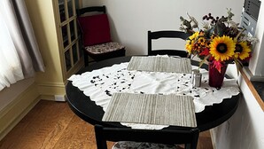 A dining area with a round table, two chairs, a vase with flowers, and a clock on the wall. -  LOVELY 1 Bedroom Apartment in the Heart of Golden (Golden)