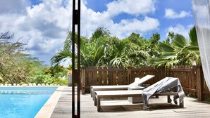 Une terrasse en bois avec des chaises longues et une piscine.