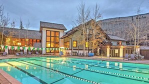 Una piscina con carriles delimitados, rodeada de edificios con amplios ventanales y montañas al fondo.