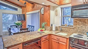 Una cocina con armarios de madera, encimeras de granito, una estufa y un comedor con una mesa y sillas.