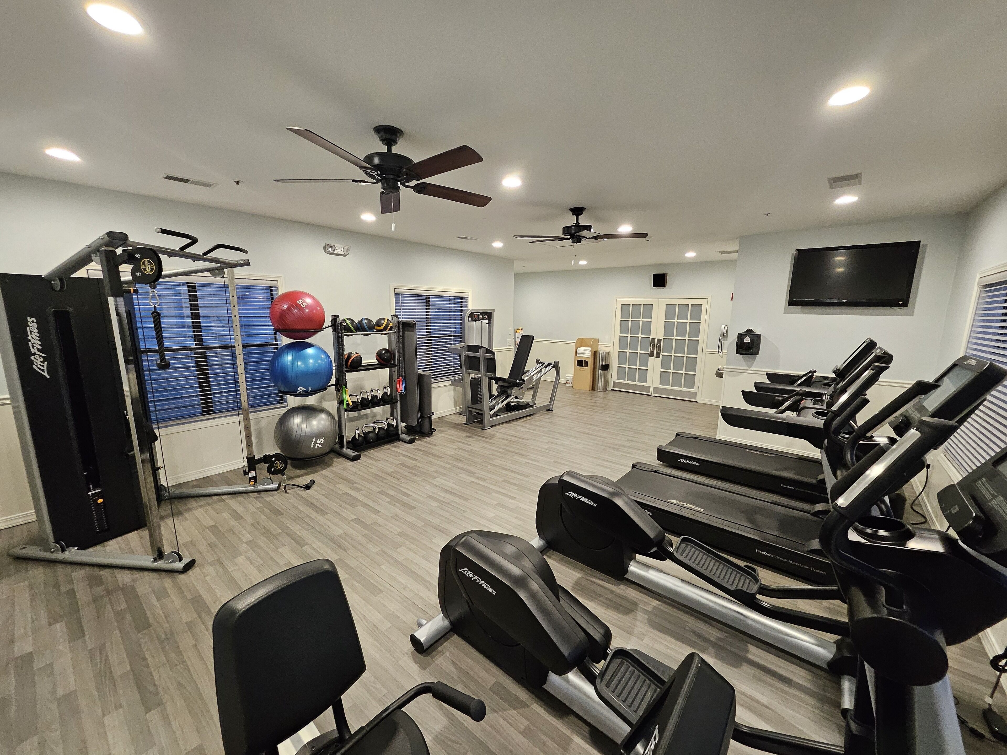 A gym with treadmills, weight machines, and exercise balls.