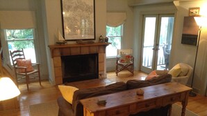 A living room with a fireplace, a sofa, a wooden coffee table, and a chair.