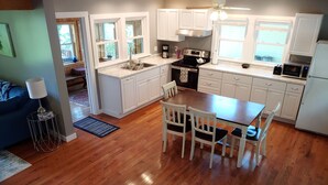 A modern kitchen with white cabinets, a wooden dining table, and a built-in oven. - SHELDRAKE SPECTACULAR LAKE VIEW (Ovid)