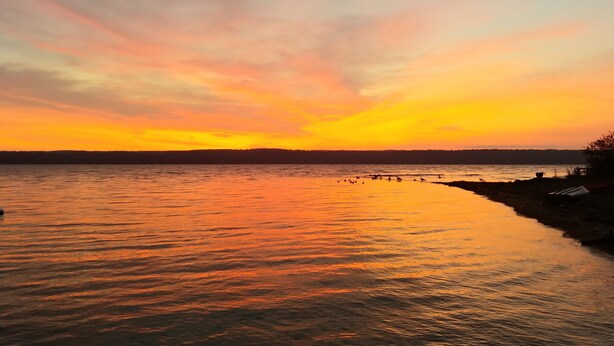 A sunset over a calm body of water with a shoreline. - SHELDRAKE SPECTACULAR LAKE VIEW (Ovid)