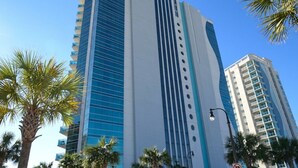 Un edificio moderno e imponente con facciata in vetro e una serie di balconi.