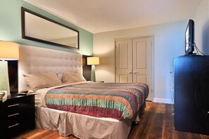 A bedroom with a bed, a dresser, a television, and a door.
