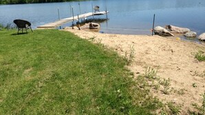 A lakeside dock with fishing rods, a chair, and a boat.