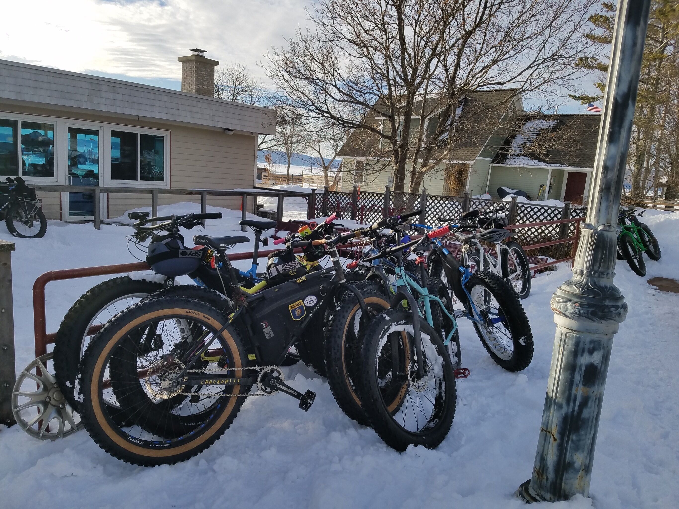 Une rangée de vélos est garée dans un espace extérieur enneigé, probablement un lieu de location ou de stockage de vélos.