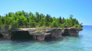 A natural rock formation with a forested area above it, surrounded by water. - Bayfield- Charming Condo, No Cleaning Fees, Jumping Off Point to Apostles (Bayfield)