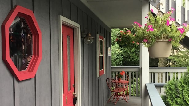 A covered porch with a red door, a hexagonal window, and a potted plant with pink flowers. - Bayfield- Charming Condo, No Cleaning Fees, Jumping Off Point to Apostles (Bayfield)