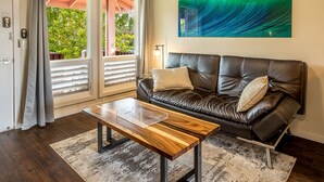 Ein Wohnzimmer mit einem Ledersofa, einem Holztisch und einem großen abstrakten Gemälde an der Wand.