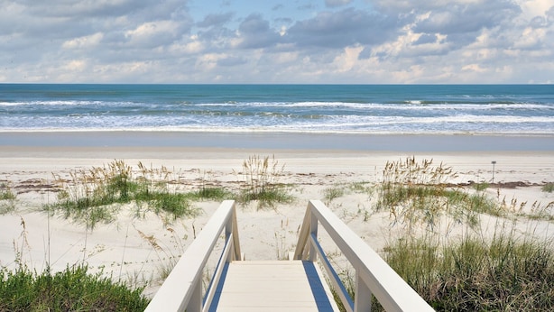 A wooden boardwalk leading to a beach with sand and sparse vegetation. - The Beach Retreat, 3 Beds, Walk to Beach, Shops & Pier, Beach Items Included (St Augustine Beach)