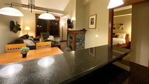 Una sala de estar moderna con una isla grande de mármol negro, chimenea y un rincón de estar acogedor con sofá y sillones.