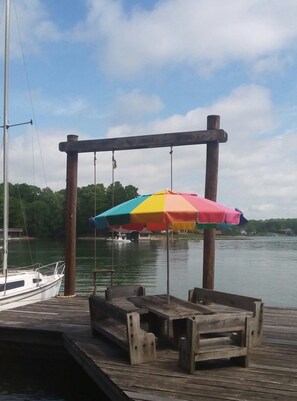 Une jetée en bois avec un parasol coloré et des bancs.