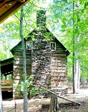 Un chalet rustique avec une façade en pierre, des poutres en bois et une cheminée.