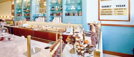 An ice cream parlor with a variety of ice cream flavors and sorbets displayed on shelves and a menu board.