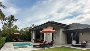 Un jardin avec une piscine, des chaises longues et un patio couvert.
