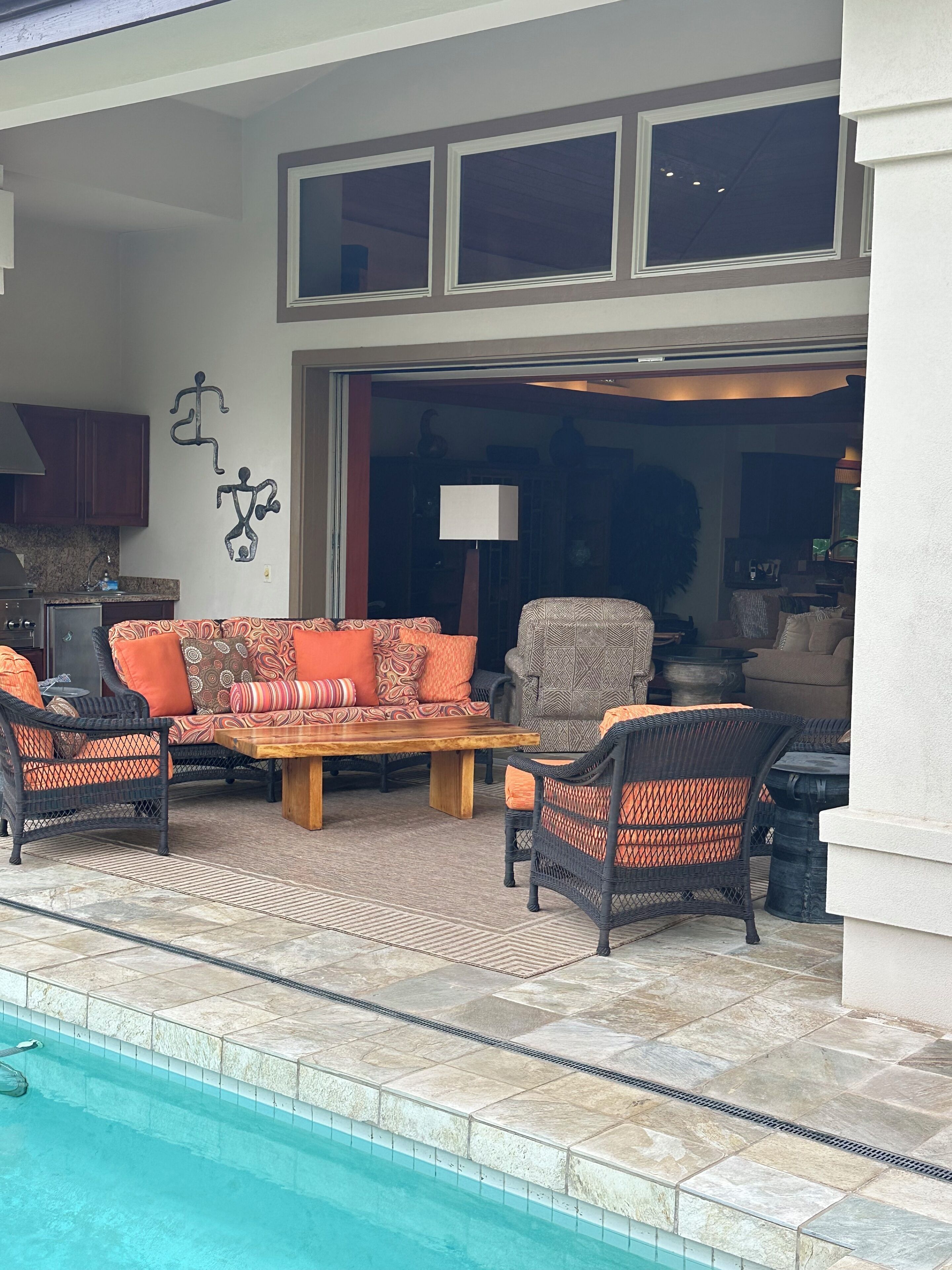 An outdoor seating area with wicker furniture and a pool.