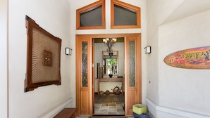 Un couloir avec un banc en bois, un miroir décoratif et un panneau fixé au mur.