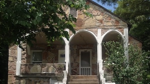 A stone house with a front porch, steps leading to the door, and a mailbox.