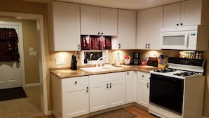 A kitchen with white cabinets, a microwave, a stove, and various kitchen items.